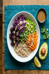 Colorful diversity grain bowl with brown rice, roasted beets, red cabbage, edamame, carrots, sesame seeds, and tahini dressing