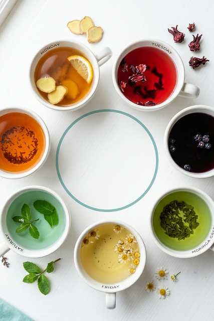 Seven herbal tea cups in weekly rotation showing ginger hibiscus bilberry and moringa herbal tea benefits schedule